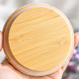 Op de afbeelding: Een cirkelvormig bamboe deksel met een natuurlijk houtnerfpatroon en een gladde, lichtbruine afwerking. Het deksel is voorzien van een doorschijnende, flexibele siliconen afdichtingsring aan de buitenrand voor een veilige afsluiting.