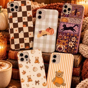 May include: Five phone cases featuring autumn-themed designs including a brown and white checkerboard with ghosts, a beige plaid with a pumpkin, a purple collage with a black cat, a cream case with teddy bears, and a white and orange striped case.