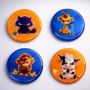 May include: Four round buttons with cartoon animal designs. A black cat with green eyes sits on an orange button. A giraffe, monkey, and cow with angry expressions are on blue and orange buttons.