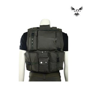 Puede incluir: Chaleco t&aacute;ctico verde oliva con m&uacute;ltiples bolsillos de varios tama&ntilde;os, asegurados con correas y botones. El chaleco se usa sobre una camiseta negra y se muestra en un maniqu&iacute;. Un logotipo de un p&aacute;jaro est&aacute; en la esquina superior derecha.