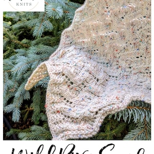 May include: A white knitted scarf with a speckled pattern, featuring a delicate lace stitch design. The scarf is draped over a green evergreen branch. The text "Wild River Scarf" is written in black cursive below the scarf.