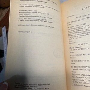 May include: Open book with text on aged paper. The left page lists publishing information, including the publisher's address and ISBN. The right page displays the table of contents, including chapter titles and page numbers. The book is a paperback.