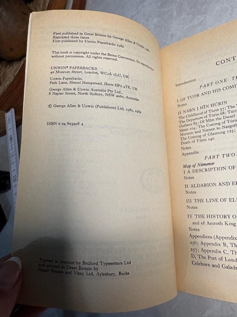 May include: Open book with text on aged paper. The left page lists publishing information, including the publisher's address and ISBN. The right page displays the table of contents, including chapter titles and page numbers. The book is a paperback.