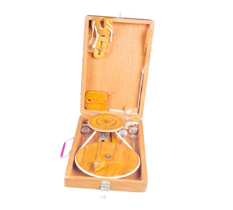 May include: A wooden box with a hinged lid, containing a small wooden wheel and other tools. The box is open and the wheel is visible. The box has a pink handle.