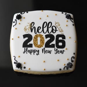 Peut inclure: Un biscuit carré avec glaçage blanc, décoré d'accents dorés et noirs. Le biscuit porte les mots "hello 2026 Happy New Year" en noir et or. De petits points dorés et des motifs floraux noirs ornent les bords.