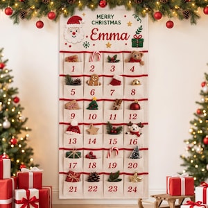 Pode incluir: Um calendário do advento de tecido branco com vinte e quatro bolsos numerados, apresentando um gráfico de Papai Noel, o texto Merry Christmas e Emma, e bordas vermelhas. Cada bolso contém pequenos itens natalinos como enfeites e brinquedos.