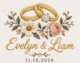 May include: An embroidery design featuring two gold wedding rings with a central floral cluster of white and pink flowers, green leaves, and small buds. Below, the text reads Evelyn & Liam in gold script, followed by the date 11.15.2026.