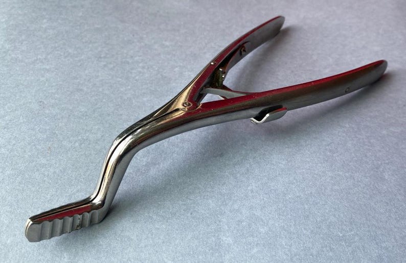 K&ouml;nnte beinhalten: Gl&auml;nzendes, silberfarbenes chirurgisches Instrument mit gebogenem Griff und gezahntem Kiefer. Das Werkzeug besteht aus Metall und scheint in gutem Zustand zu sein. Das Instrument ist f&uuml;r den medizinischen Gebrauch bestimmt.