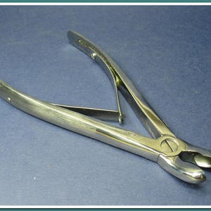Peut inclure: Une paire de pinces chirurgicales argentées avec une poignée incurvée et une extrémité coupante.