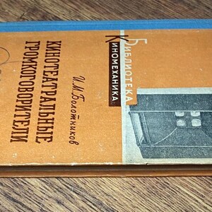 May include: A vintage book with a tan cover and blue spine, titled in Russian. The cover features text and an illustration of a projector. The book is titled "Theater Speakers" and is part of the "Inomekhanika" library.