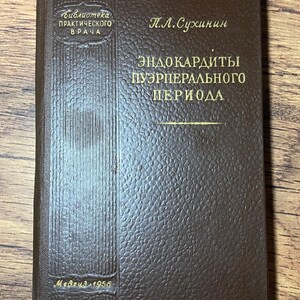 Puede incluir: Un libro marrón vintage con letras doradas. La portada presenta el título "Эндокардиты пуэрперального периода" y el nombre del autor, "П.Л. Сухинин." El libro es de la serie "Библиотека практического врача", publicado por Medgiz en 1956.