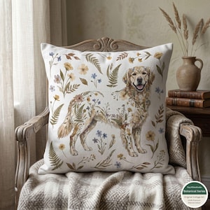 May include: Square throw pillow featuring a Golden Retriever illustration adorned with floral and fern patterns in shades of brown, yellow, and blue. The pillow is set against a neutral background, creating a cozy, cottage-style aesthetic. The pillow is made of 100% natural cotton.