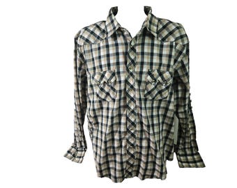 May include: A long-sleeved, button-down shirt with a plaid pattern in black, tan, and white. The shirt has two chest pockets with button closures and a pointed collar. The cuffs also have button closures. The shirt is made of a woven fabric.