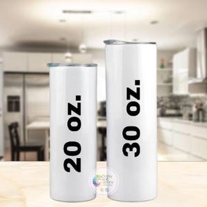 Puede incluir: Dos vasos aislados blancos con texto negro que indica tama&ntilde;os de 591 ml y 887 ml. Los vasos tienen tapas plateadas y son de forma cil&iacute;ndrica. El fondo es una cocina borrosa.