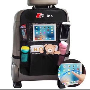 Könnte beinhalten: Schwarzer Autositz-Organizer mit mehreren Taschen und einem transparenten Tablethalter. Mit dem Logo "S line" in Rot und Weiß. Enthält einen Teddybären, eine Wasserflasche und Snacks.