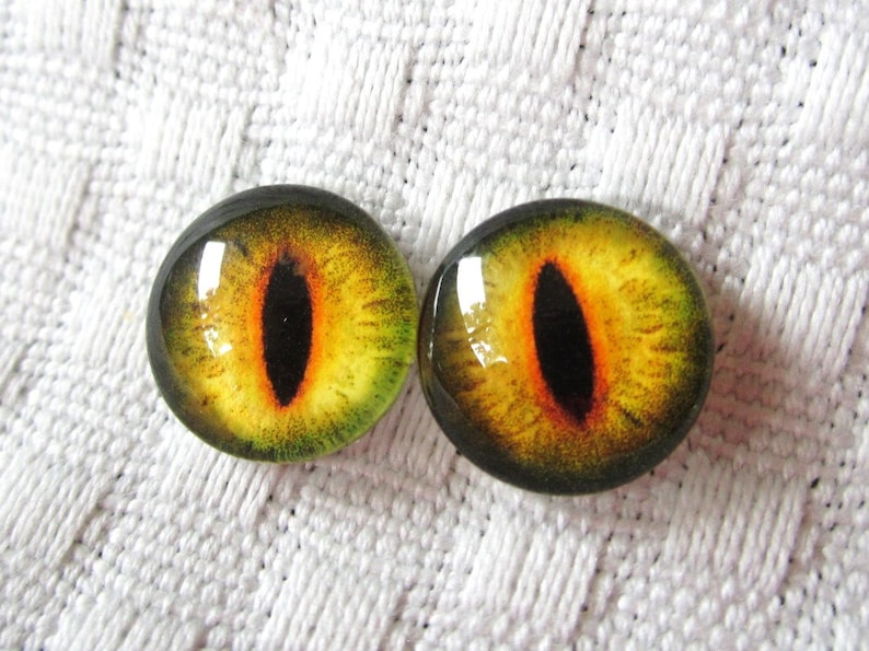 May include: A pair of yellow and green glass eyes with black pupils. The eyes have a realistic cat-like appearance.