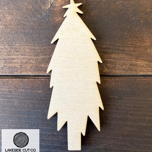 May include: Unfinished wooden Christmas tree cutout, 1/8" thick, made of Baltic birch plywood. The tree has a star at the top and a trunk at the bottom. The text "1/8" THICK WOOD CUTOUT" is at the top.