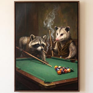 May include: A framed oil painting depicting a raccoon and an opossum wearing brown waistcoats, playing billiards on a green table. Both animals hold cigars with visible smoke rising, and pool cues are positioned over a rack of colourful billiard balls.