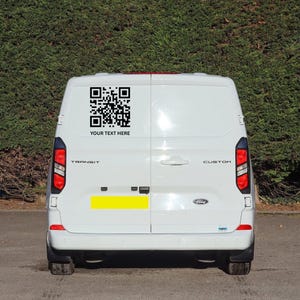 May include: White Ford Transit van with a black QR code and the text "YOUR TEXT HERE" on the back. The van has red taillights and a yellow rectangle. The word "TRANSIT" is visible.