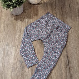 Könnte beinhalten: Babyhose mit floralem Muster in Blau-, Rot- und Weißtönen. Die Hose ist aus einem weichen Stoff gefertigt und hat eine bequeme Passform. Die Hose ist für Babys und Kleinkinder konzipiert.