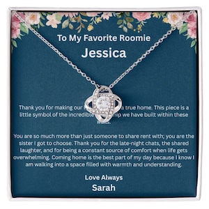 May include: A silver necklace with a pendant featuring a central clear stone surrounded by a swirling design. The necklace is presented on a card with text that reads "To My Favorite Roomie Jessica" and a heartfelt message.