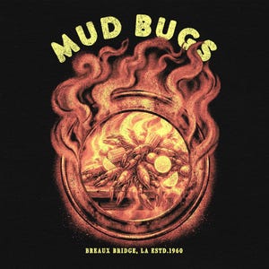 Può includere: Un design grafico con le parole "MUD BUGS" in giallo, sopra un'immagine circolare di gamberi di fiume, mais e limoni, circondata da fiamme. Il testo "BREAUX BRIDGE, LA ESTD.1960" è in basso, il tutto su sfondo nero.