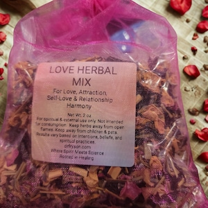 May include: A translucent pink organza drawstring bag filled with a dried herbal mixture. A rectangular label on the front reads: LOVE HERBAL MIX, For Love, Attraction, Self-Love & Relationship Harmony, Net Wt. 2 oz, For spiritual & external use only.
