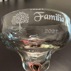 K&ouml;nnte beinhalten: Ein klares Glas-Margarita-Glas mit einem gravierten Design eines Baumes mit Wurzeln und dem Wort "Familia" und dem Jahr "2023" am Rand.