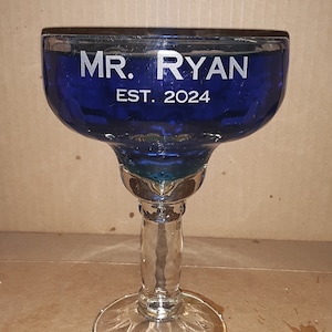 K&ouml;nnte beinhalten: Ein blaues Glas-Margarita-Glas mit dem Text "MR. RYAN EST. 2024" auf der Seite.