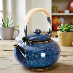 May include: A blue ceramic teapot with a woven handle and black metal accents. The teapot has a round body, a lid with a small knob, and a spout. The teapot is sitting on a wooden surface.