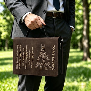 May include: A brown leather briefcase with the text "TO MY LOVING DAD" and a graphic of hands. The briefcase has a zipper closure and a handle. The text "May the LORD bless you and PROTECT you" is also visible.