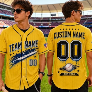 Könnte beinhalten: Ein gelbes Baseballtrikot mit schwarzen Nadelstreifen, schwarzer Umrandung und durchgehender Knopfleiste. Die Vorderseite zeigt den Text TEAM NAME mit einem blauen Pinselstrich-Grafikdesign und der Nummer 00. Hinten stehen CUSTOM NAME, 00, ein Baseball und EST. 2026.