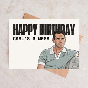 May include: A greeting card with the text "HAPPY BIRTHDAY" above "CARL'S A MESS" in black. The card features an illustration of a man in a light blue polo shirt. The card is on a brown envelope.