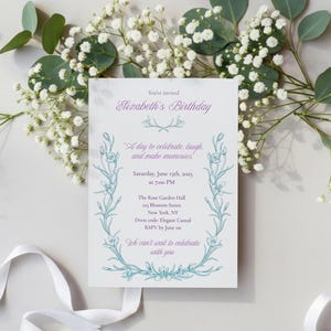 Puede incluir: Una tarjeta de invitación blanca con texto morado y turquesa e ilustraciones florales, que anuncia el cumpleaños de Elizabeth. La tarjeta está rodeada de flores blancas y vegetación, con una cinta blanca en la parte inferior.