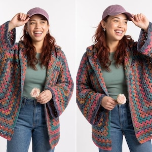 May include: A colorful, hooded crochet jacket with wide sleeves. The jacket features a granny square pattern in shades of pink, blue, orange, and green. The person in the image is wearing a purple baseball cap and blue jeans.