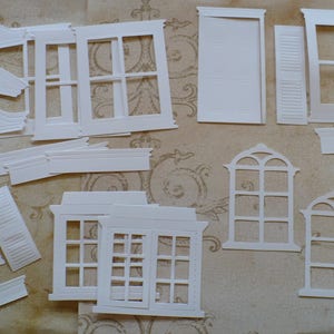 May include: A set of white paper die cuts in the shape of windows and shutters. The die cuts are perfect for scrapbooking, card making, and other paper crafts.