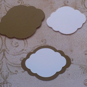 May include: Three blank paper labels with scalloped edges. The labels are in the shape of a cloud. One label is brown, and the other two are white with brown borders.