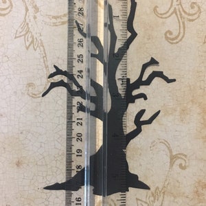 Op de afbeelding: Zwarte papieren silhouet van een kale boom met takken die omhoog en naar buiten reiken. De boom is ongeveer 15 cm hoog en wordt gemeten met een liniaal.