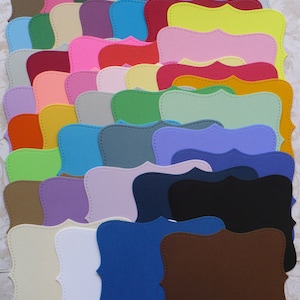 May include: A set of 30 colorful paper frames with scalloped edges and a stitched design. The frames are arranged in rows and are in various shades of red, blue, green, yellow, orange, purple, and brown.