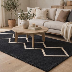 May include: A rectangular area rug featuring a deep black base color with a prominent white geometric pattern consisting of interconnected diamond shapes. The rug has a textured, tufted surface and is positioned on a light-colored wooden floor.