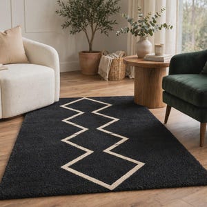 May include: A rectangular area rug featuring a deep black, textured pile surface with a prominent, centered geometric pattern composed of thin, light beige lines that form a continuous, repeating zigzag or diamond-like shape across the center.