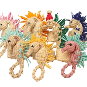 Peut inclure: Collection d'ornements en forme d'hippocampes tressés de différentes couleurs. Chaque hippocampe a une crinière de couleur différente, notamment rose, orange, jaune, vert et bleu. Certains ont de petits détails décoratifs comme un bonnet de Père Noël.