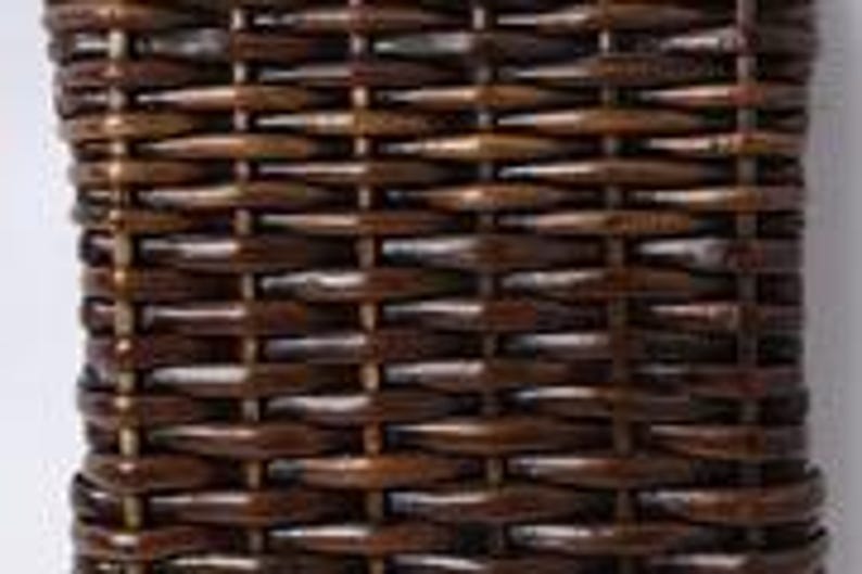 May include: Close-up of a rectangular, woven basket with a dark brown finish. The basket's weave pattern is tightly interlaced, creating a textured surface. The basket is likely made of natural materials, and the dark brown color gives it a rustic appearance.