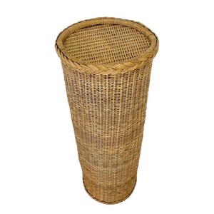 May include: A tall, cylindrical wicker basket with a woven lid. The basket is made of light brown wicker and has a braided trim around the top. The basket is empty and stands on a white background.