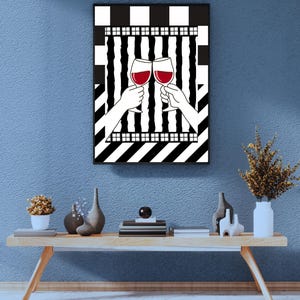 May include: A framed art print featuring two hands toasting with wine glasses filled with red wine. The background has a black and white geometric pattern. The artwork is displayed on a blue wall above a wooden table with decorative items.