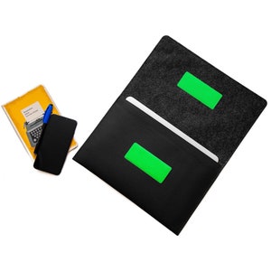 Könnte beinhalten: Schwarze Laptop-Hülle aus Filz mit grünem Etikett. Die Hülle ist geöffnet und zeigt einen weißen Laptop-Bildschirm.
