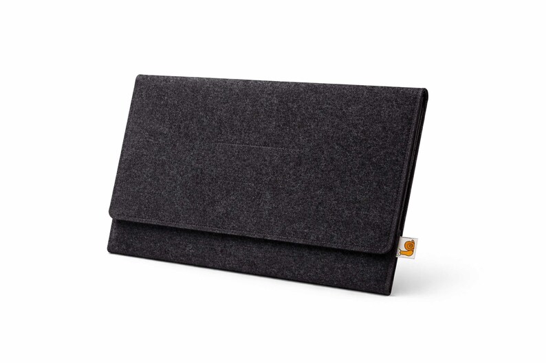 May include: A dark gray felt laptop sleeve with a flap closure. The sleeve has a rectangular shape and a small, rectangular pocket on the front. A small tag is attached to the bottom right corner.