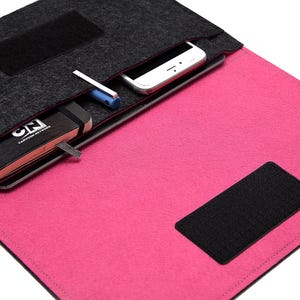 May include: A felt laptop sleeve in gray and pink, with a black Velcro closure. The sleeve has a pocket containing a smartphone, a pen, and a black notebook with the text "CN CARTOON NETWORK".