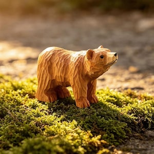 May include: A small, light brown wooden bear figurine featuring visible hand-carved chisel marks across its entire body. The bear is depicted in a standing position with a smooth, dark-coloured nose and eyes, showcasing a textured, rustic finish.