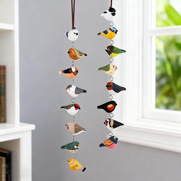 Peut inclure: Deux guirlandes d'ornements d'oiseaux en bois peints, suspendues à des cordons bruns. Chaque oiseau présente des motifs et des couleurs détaillés, notamment du bleu, du jaune, de l'orange et du rouge. Des anneaux métalliques relient les oiseaux, créant un mobile décoratif.